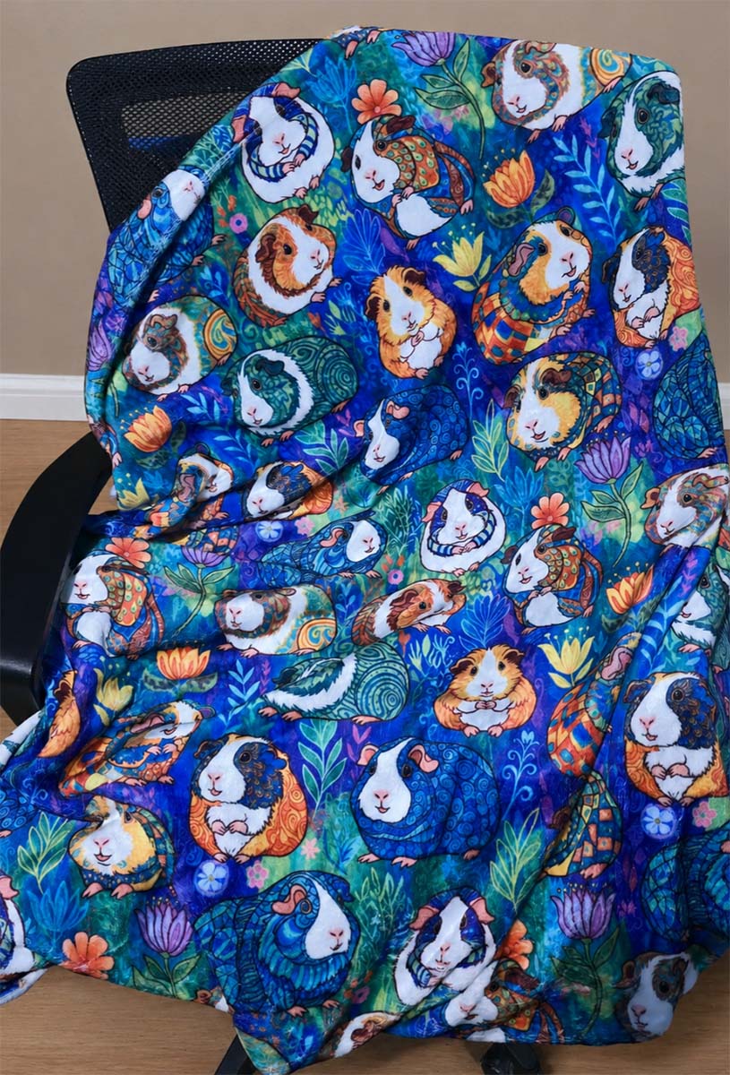 Colorful blanket with guinea pig pattern draped over a chair - Blue Paisley Piggies in Fleece