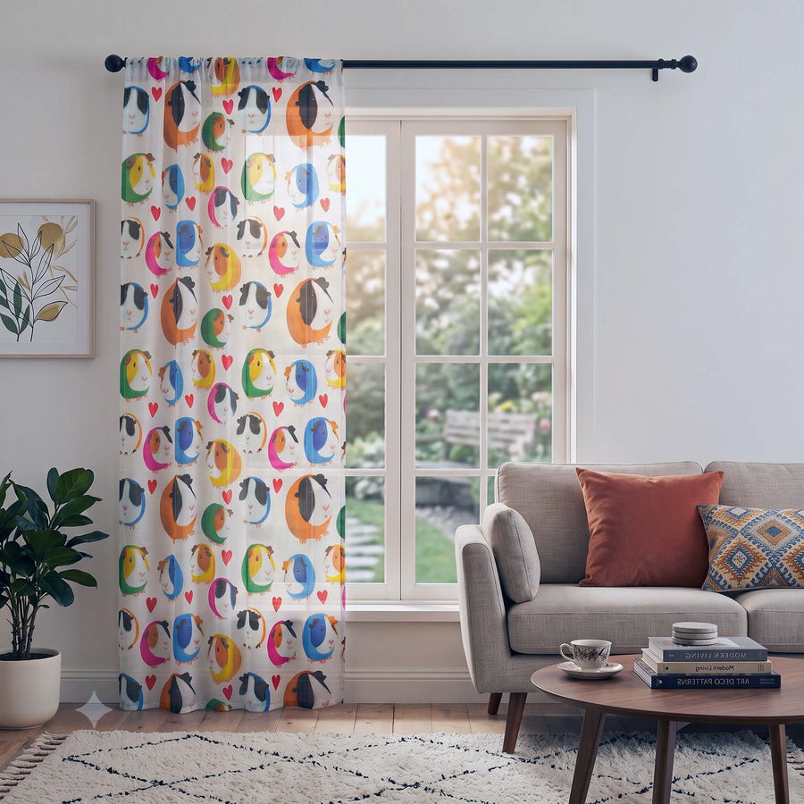 A pair of white curtain panels featuring a colorful pattern of guinea pigs, hanging on a black rod in a bright, modern living room next to a window.
