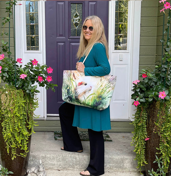 Teresa modeling the WHEEKender TOTE with a white guinea pig in grass and hay
